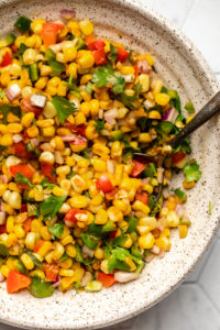 close up photo of bowl of pan grilled corn salsa with spoon in bowl