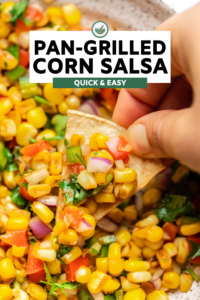 hand dunking tortilla chip into bowl of pan grilled corn salsa