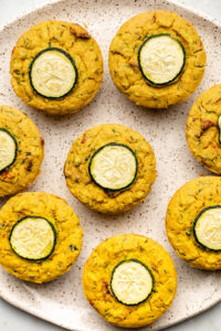 cooked savory zucchini muffins arranged on white speckled plate