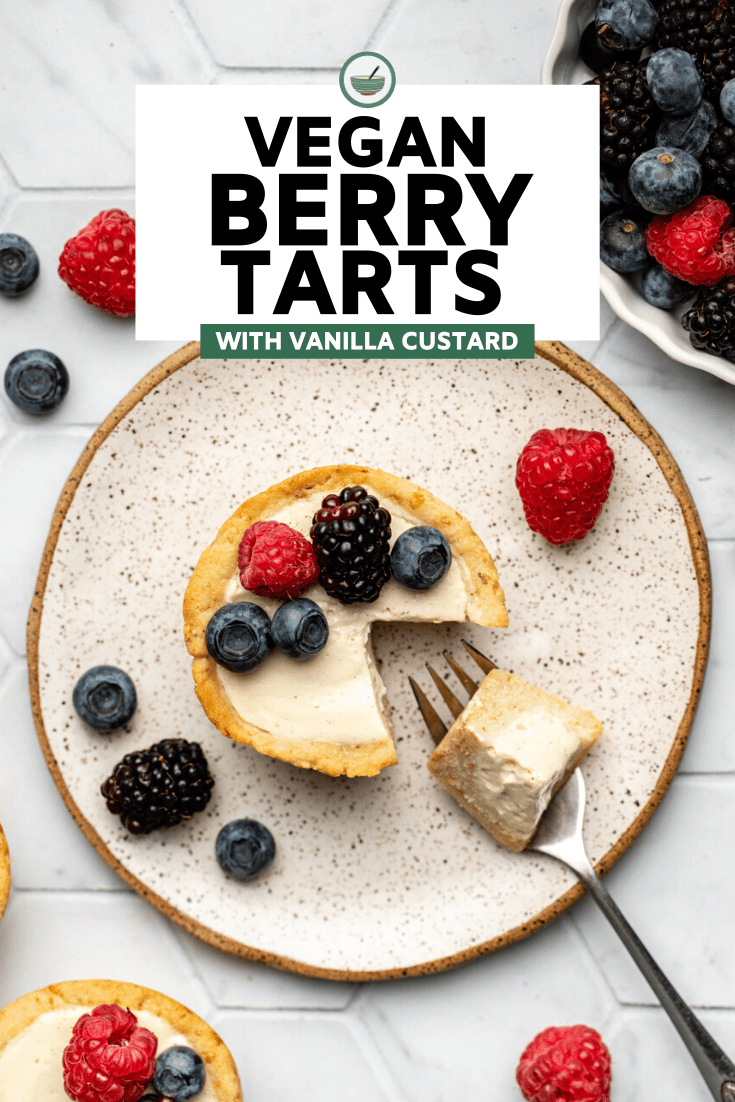berry tart on white speckled plate with bite taken out of it topped with fresh berries