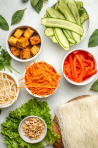 ingredients for vemicelli noodle bowls in small white bowls arranged on marble countertop