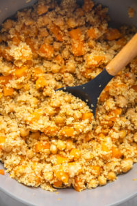cooked butternut squash and quinoa in large bot with wooden spoon