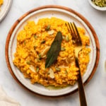plate of pumpkin risotto topped with vegan parmesan and fried sage leaf
