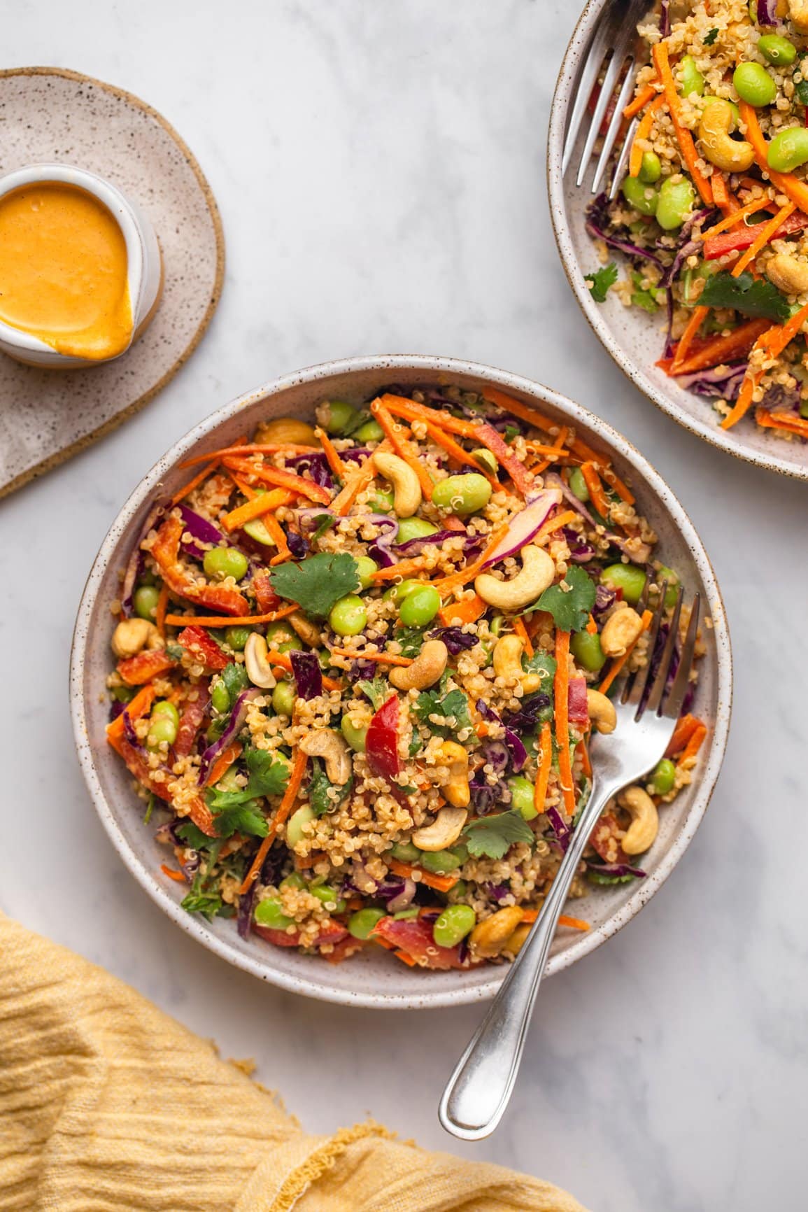 two bowls of rainbow quinoa salad with forks on marble background