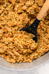 cooked rice in peas in large pot with wood spoon scooping a serving out of it