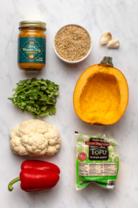 ingredients for pumpkin curry arranged on a marble background