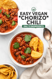 two bowls of vegan chorizo chili topped with cilantro and served with tortilla chips on the side