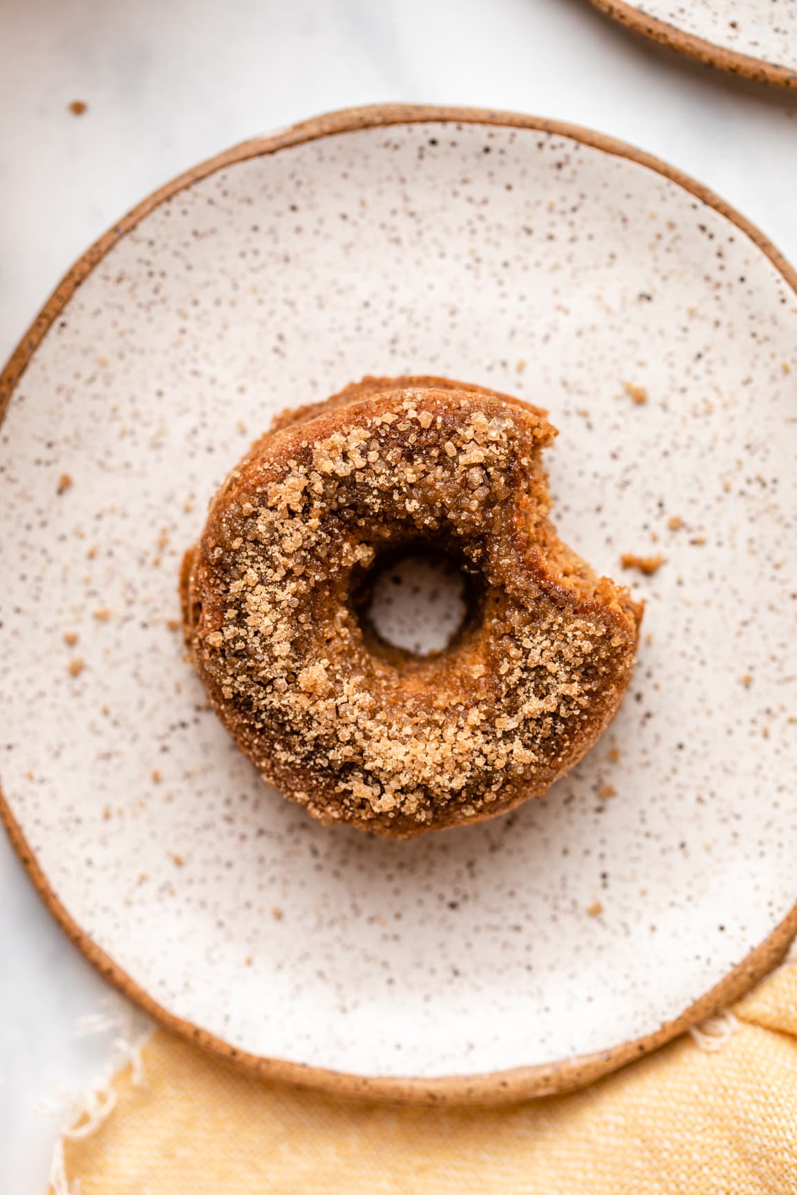 baked apple cider donut with bite taken out of it on white plate