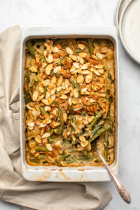 cooked green bean casserole in white dish with serving spoon