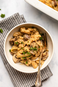 no boil vegan mushroom stroganoff in topped with parsley and black pepper in white bowl on marble countertop