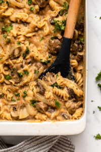 no boil baked vegan mushroom casserole topped with fresh parsley and wooden serving spoon