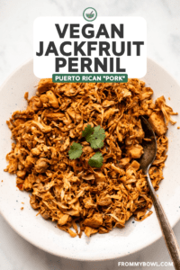 jackfruit pernil in white bowl next to serving dishes of arroz con gandules and tostones