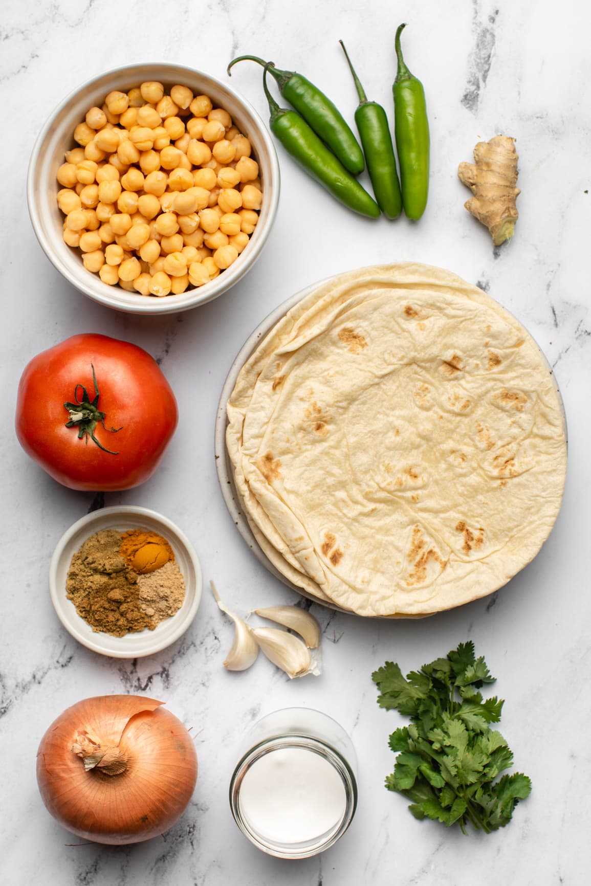 ingredients for chana kathi rolls in small white bowls on marble background