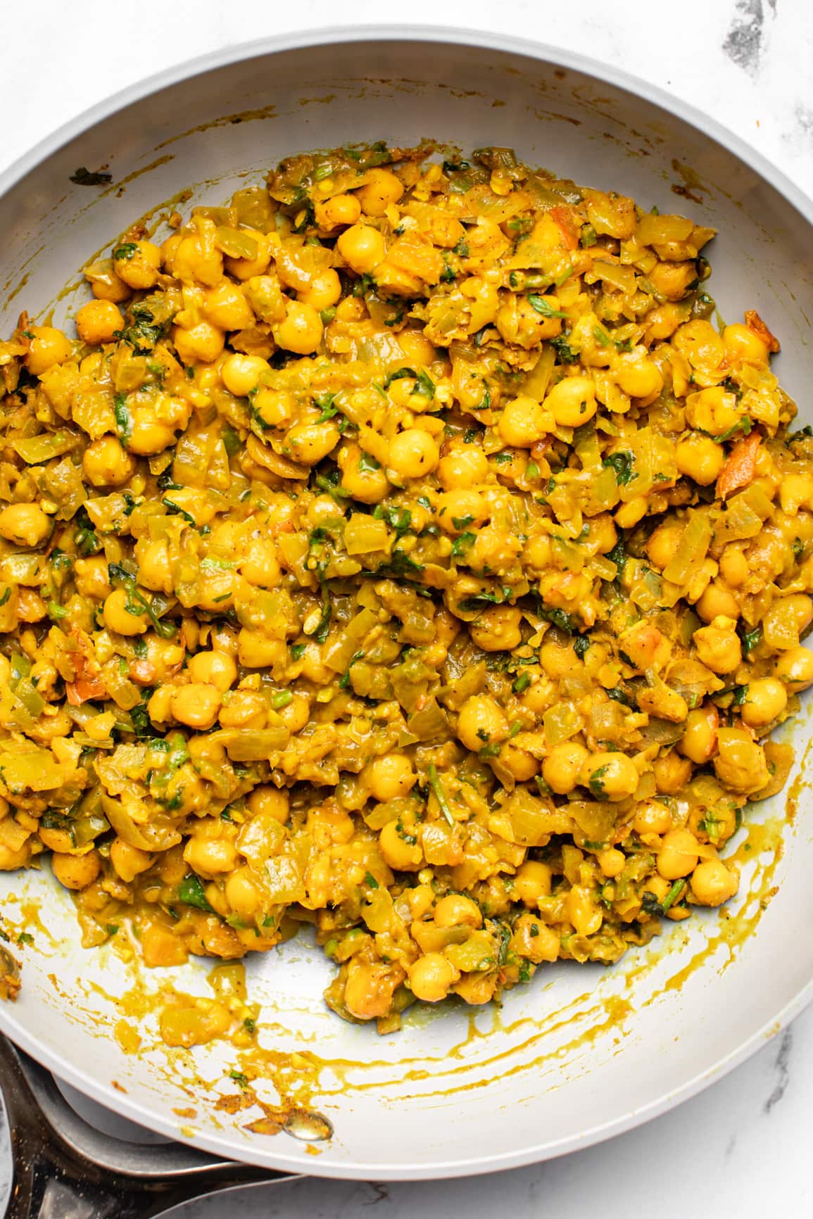 cooked chana, or chickpea curry, in white nonstick pan