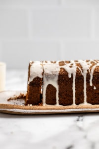 side shot of sliced gingerbread loaf with icing drizzled over the top of it