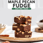 stack of maple pecan fudge with bite taken out of top piece on white speckled plate on marble countertop