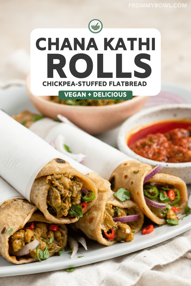 chana kathi rolls wrapped in parchment paper on white serving plate next to tomato and mint chutney