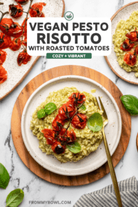 plate of pesto risotto topped with tomatoes on wood cutting board on marble countertop