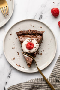fork cutting into piece of no bake chocolate tart topped with coconut cream and a raspberry