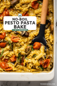 no boil pesto pasta with mushrooms and tomatoes in white casserole dish topped with fresh basil