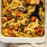 no boil pesto pasta bake in white casserole dish topped with fresh basil