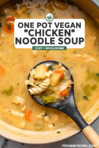 large pot of chicken noodle soup with wooden soup ladle scooping soup out of pot