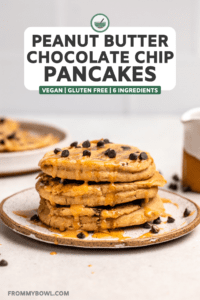 stack of 3 peanut butter chocolate chip pancakes on white plate topped with maple syrup, peanut butter, and more chocolate chips