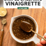 hand using spoon to mix balsamic vinaigrette in white bowl