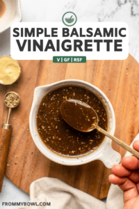 hand using spoon to mix balsamic vinaigrette in white bowl