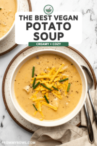 bowl of vegan potato soup topped with cheddar cheese and chives