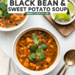 two bowls of black bean sweet potato soup topped with cilantro with lime wedges on the side