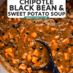 large pot of chipotle black bean soup with wooden ladle stirring soup after it has been blended