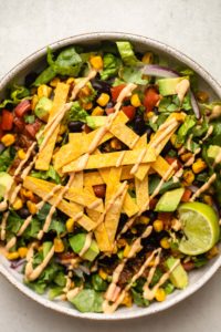 close up photo of vegan taco salad topped with baked tortilla strips and a drizzle of chipotle mayo