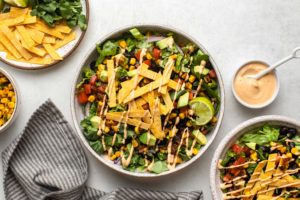 two vegan taco salads topped with tortilla strips and chipotle mayo