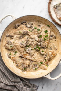 large white pan of tempeh in mushroom sauce topped with fresh parsley