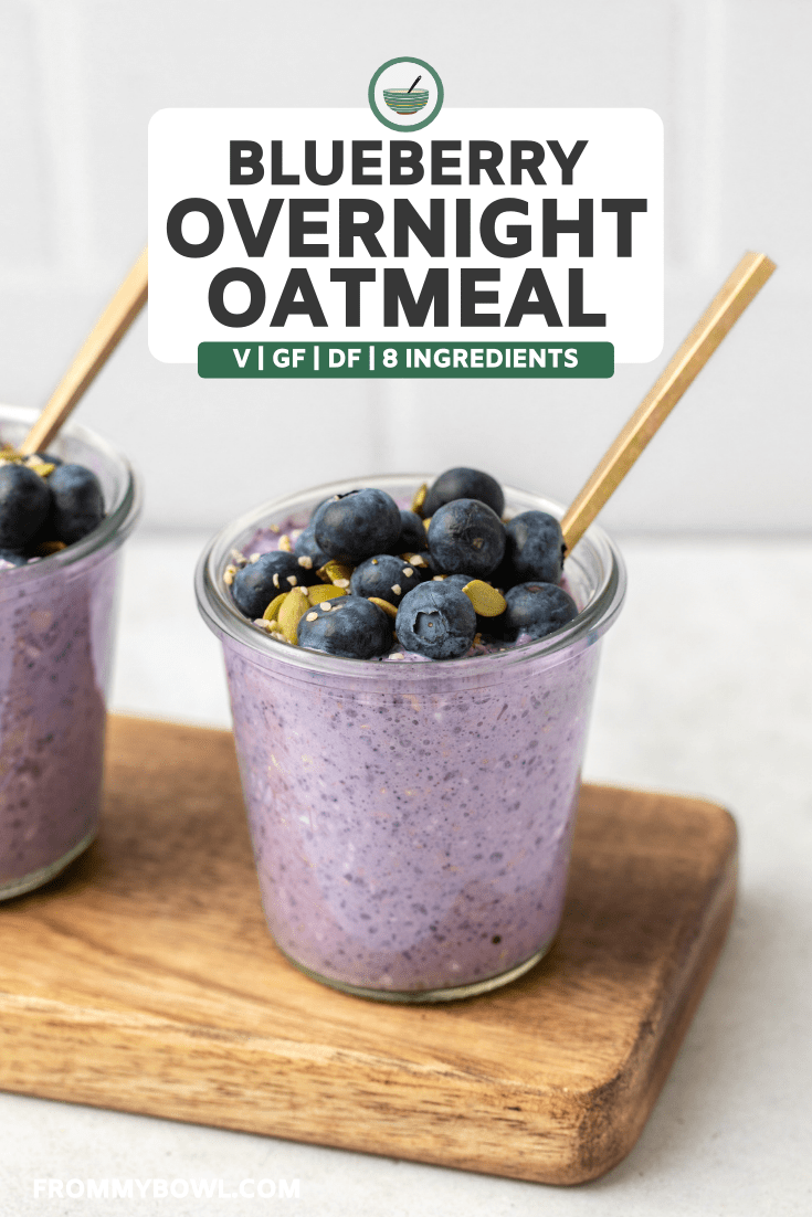jar of blueberry overnight oatmeal on wood serving tray topped with fresh blueberries and hemp hearts. A gold spoon sits in the jar as well.