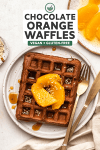 one chocolate orange waffle on white plate topped with hemp hearts orange slices and maple syrup