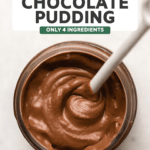 small glass jar of chocolate pudding with white ceramic spoon scooping pudding to show texture.