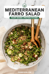Mediterranean Farro Salad in large white bowl with wooden serving spoons