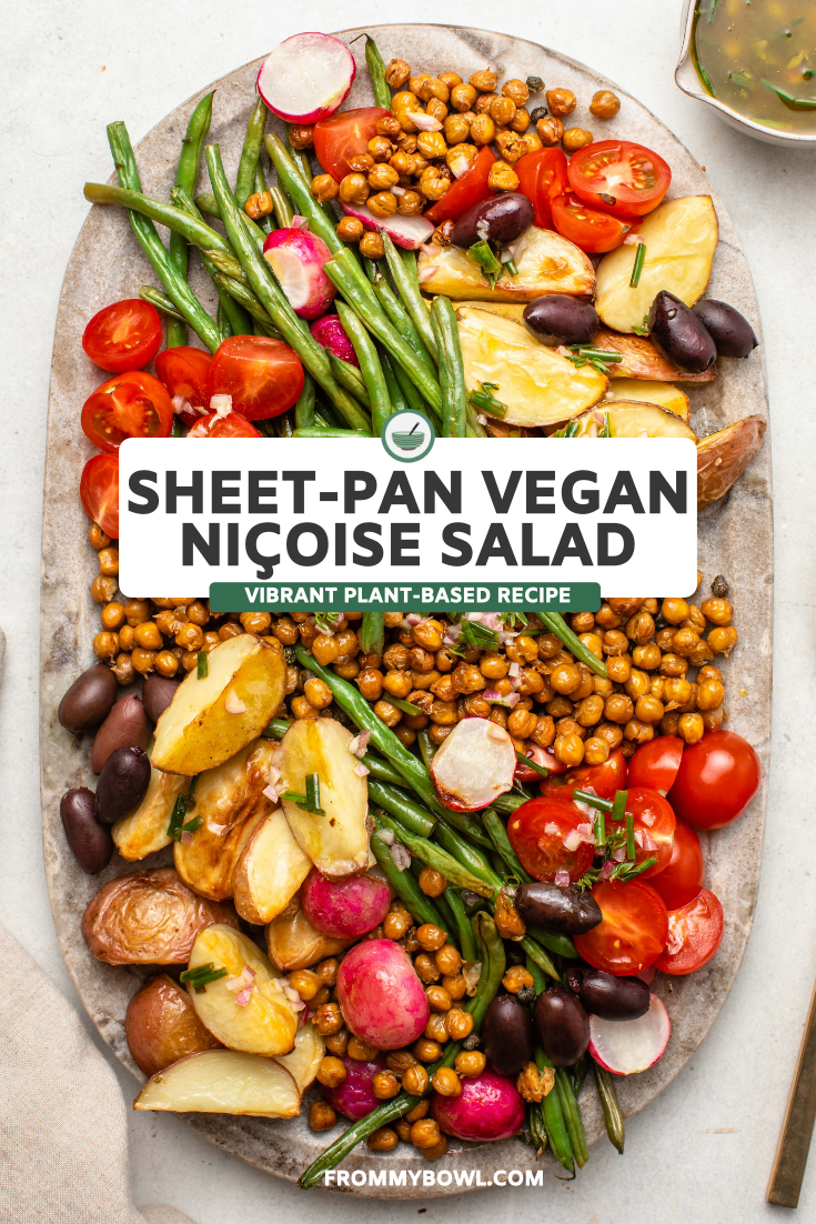 Large stone serving tray of vegan niçoise salad, with dressing on the side and gold serveware