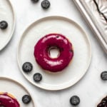 Baked Blueberry Donuts on small white plates with fresh blueberries on marble background