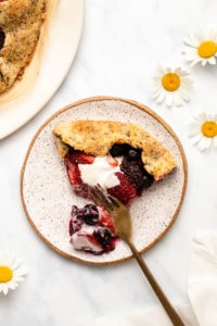 slice of berry galette on small white plate with gold fork