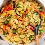 One Pot pasta in light cream sauce with squash, bell pepper, carrots, broccoli, and peas on white background