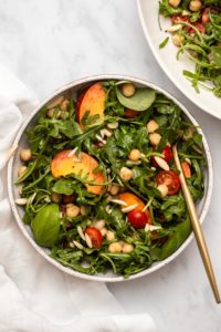 Peach & chickpea salad in small serving bowl with gold fork on marble background