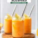 3 glasses of cantaloupe slushie topped with a lime wedge and a metal straw