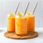 Cantaloupe Slushie in 3 glasses with a silver straw and a lime