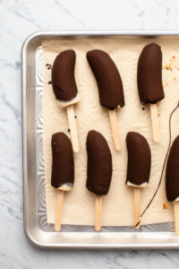 Chocolate covered banana pops on a baking sheet