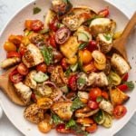 Everything bagel panzanella salad with colorful tomatoes in white bread with wooden serving spoons on marble background