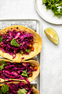 Overhead shot of 3 tacos topped with red cabbage and cilantro
