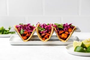 3 tacos with corn tortillas, filled with a BBQ filling and topped with a colorful cabbage slaw